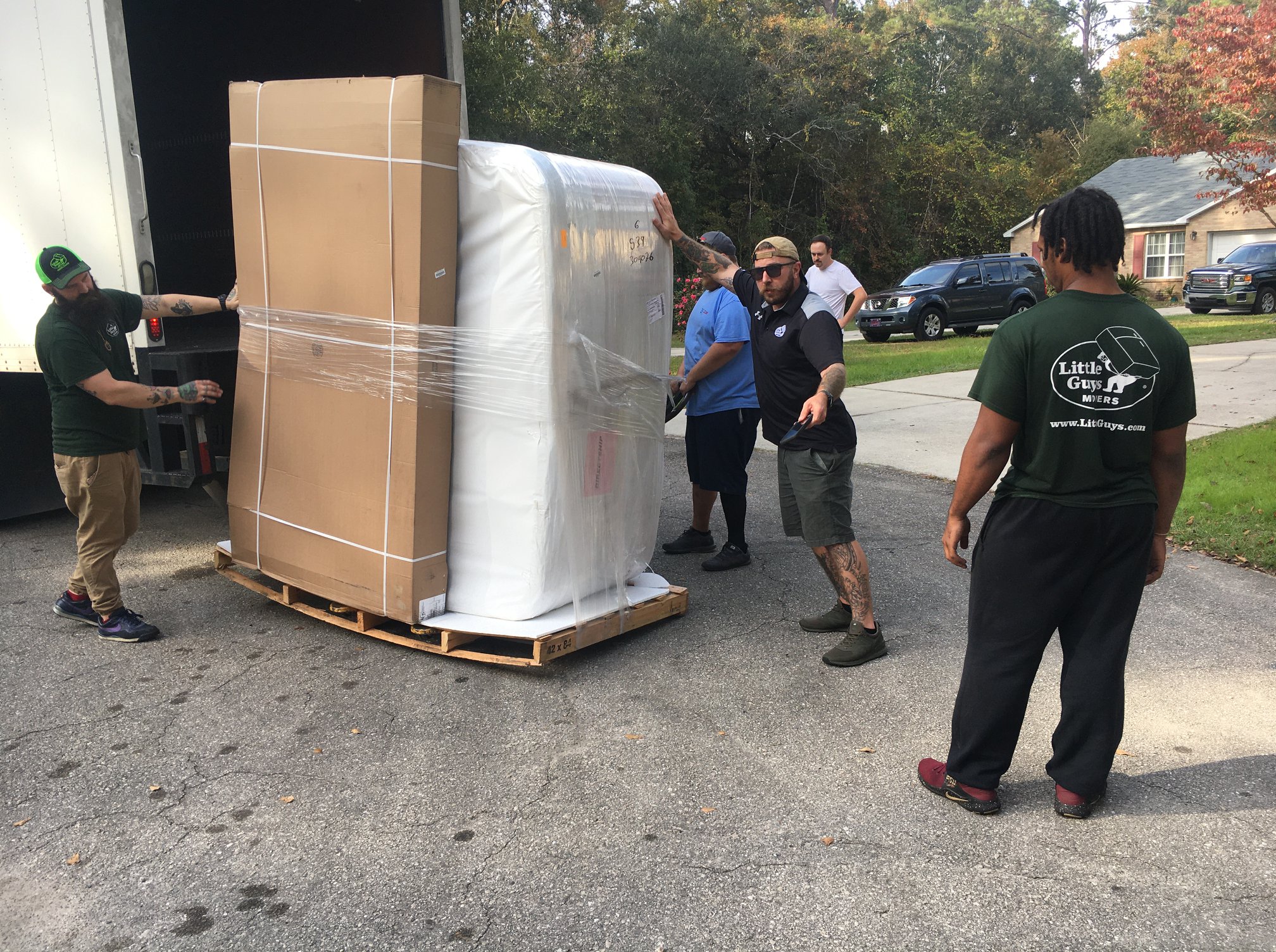 Four movers moving a hot tub into a truck