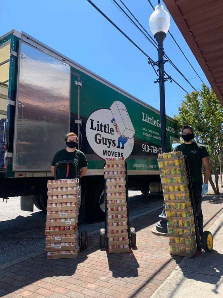 Little Guys Movers employees in front of truck with can food donations