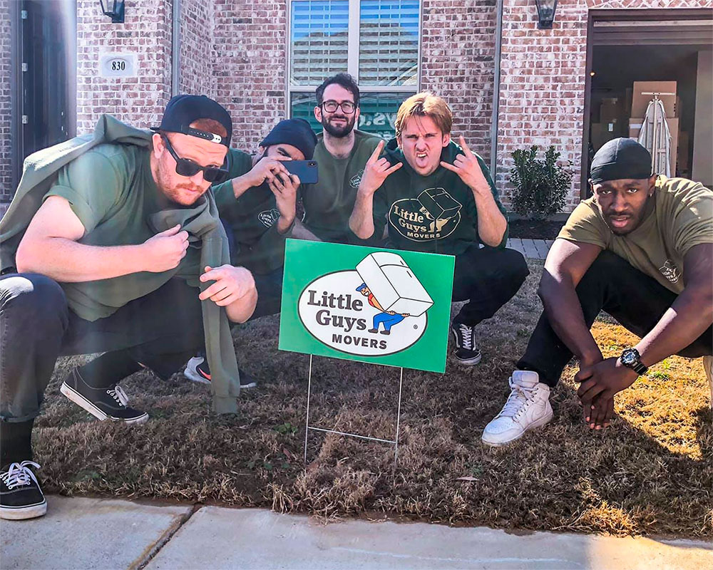 A crew of Little Guys posing with a shiny new yard sign