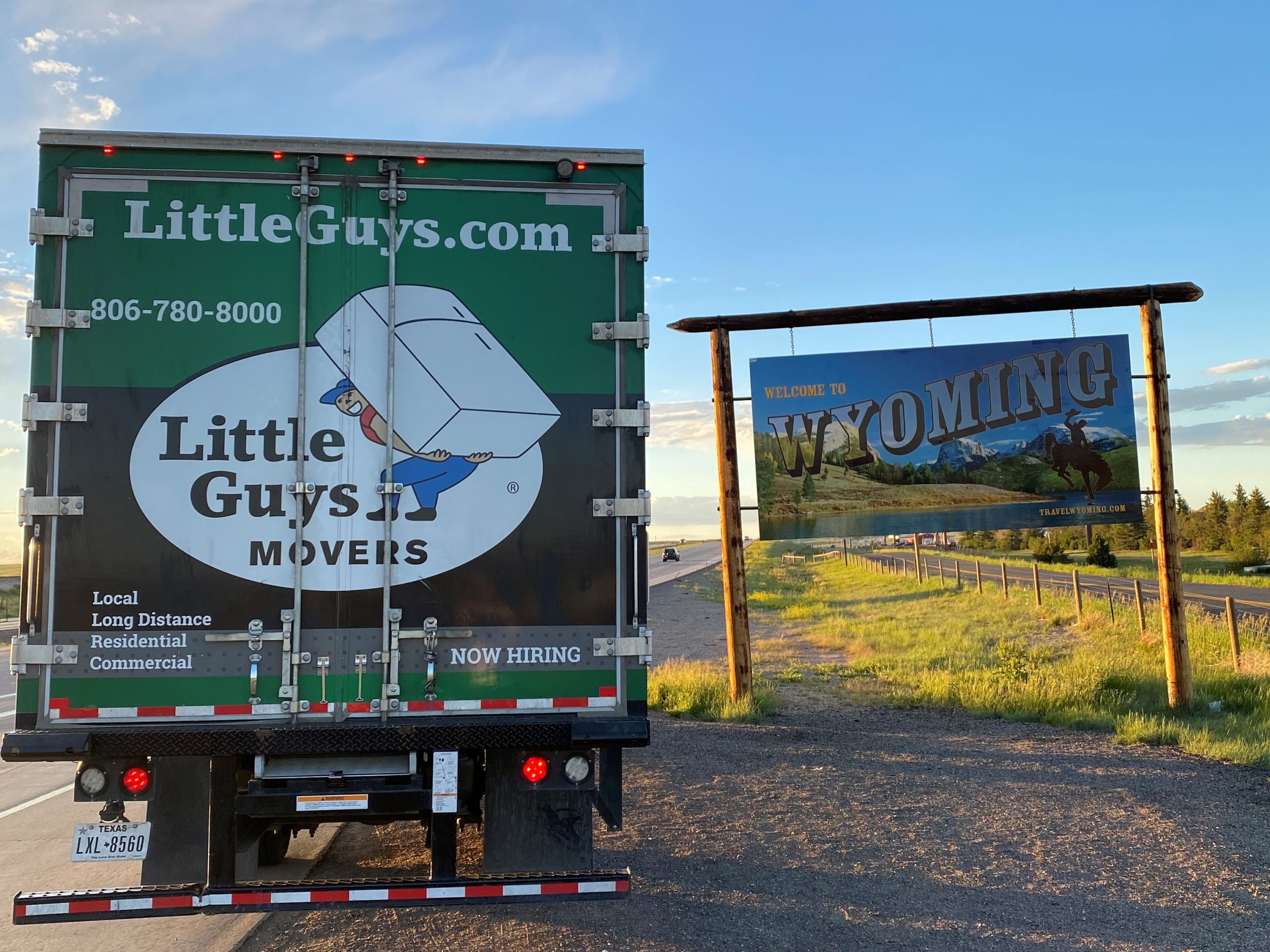 Little Guys Movers truck in front of Wyoming state sign