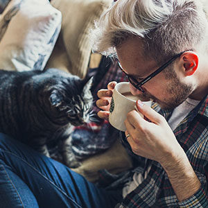 male sipping coffee next to cat