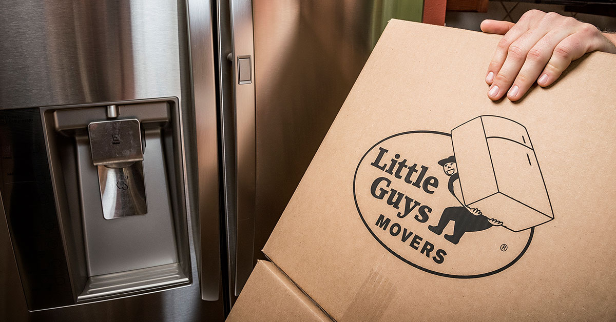 close up of a hand on a moving box with the Little Guys Movers logo