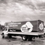 black and white photo of a Little Guys Movers moving truck under a cloudy sky