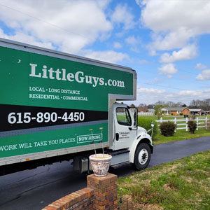 A Little Guys Movers moving truck drives through a Nashville neighborhood