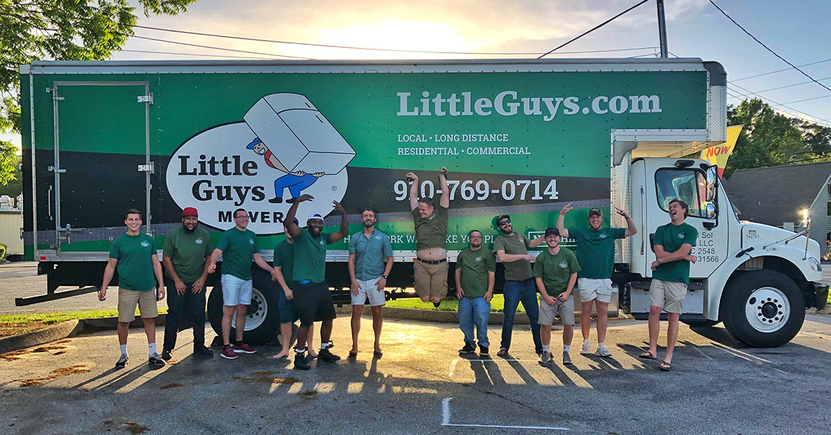 Wilmington movers pose ecstatically in front of moving truck.