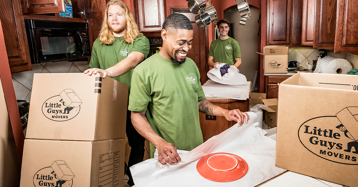 Three movers from Little Guys Movers pack up a kitchen with care.