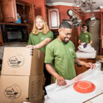 Three movers from Little Guys Movers pack up a kitchen with care.