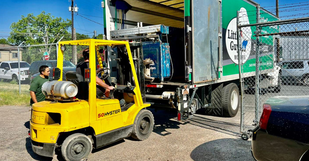 Little Guys use a forklift to put a printing press inside of their truck.