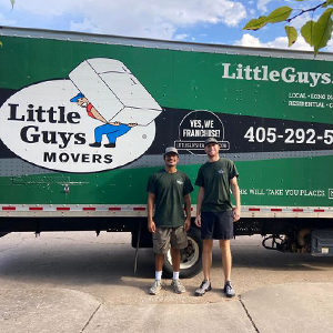 Two Little Guys stand in front of a moving truck.
