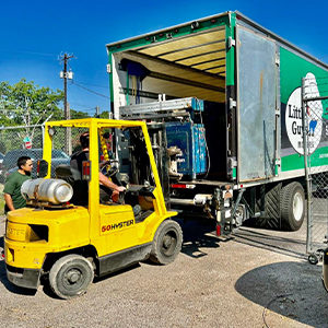 Little Guys use a forklift to put a printing press inside of their truck.