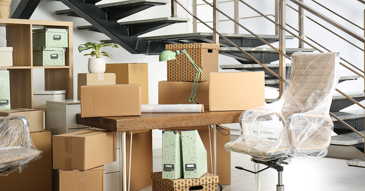A cluster of boxes and furniture is placed near a staircase.