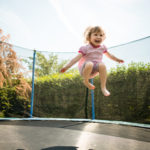 A young child jumps in the air on a trampoline.