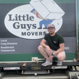 Little Guys Movers Greensboro manager sits at the end of a moving truck.