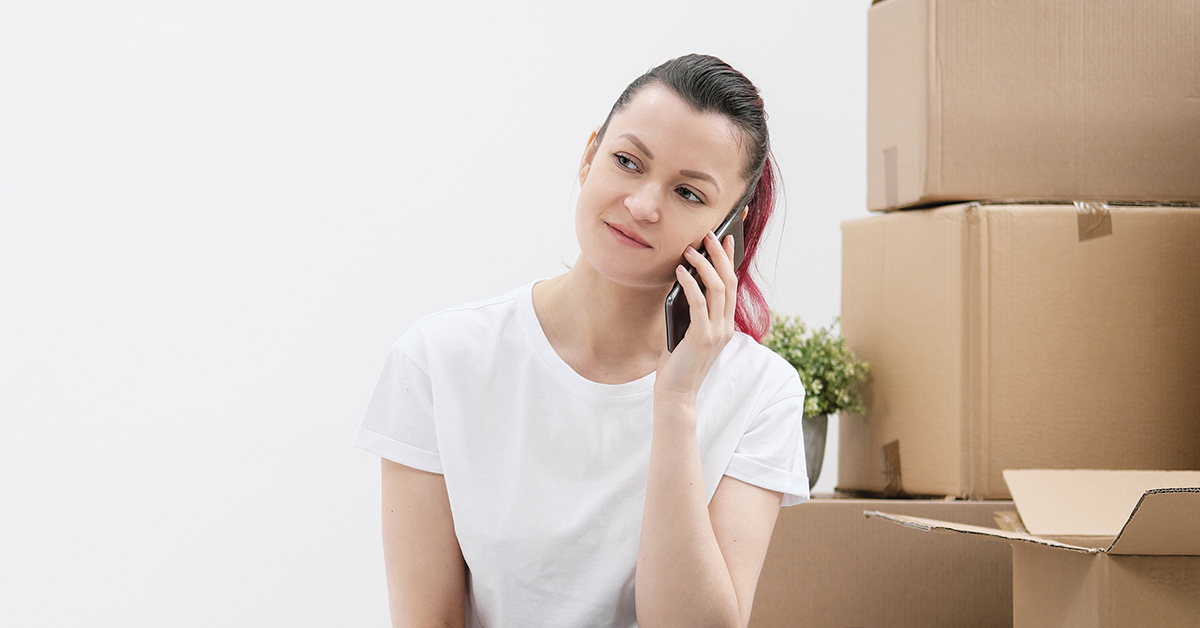 A person is on the phone with moving boxes in the background