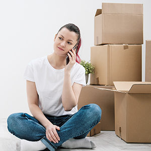 A person is on the phone with moving boxes in the background