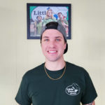 A Little Guys mover with green t-shirt and ball cap smiles for the camera at our Wilmington location