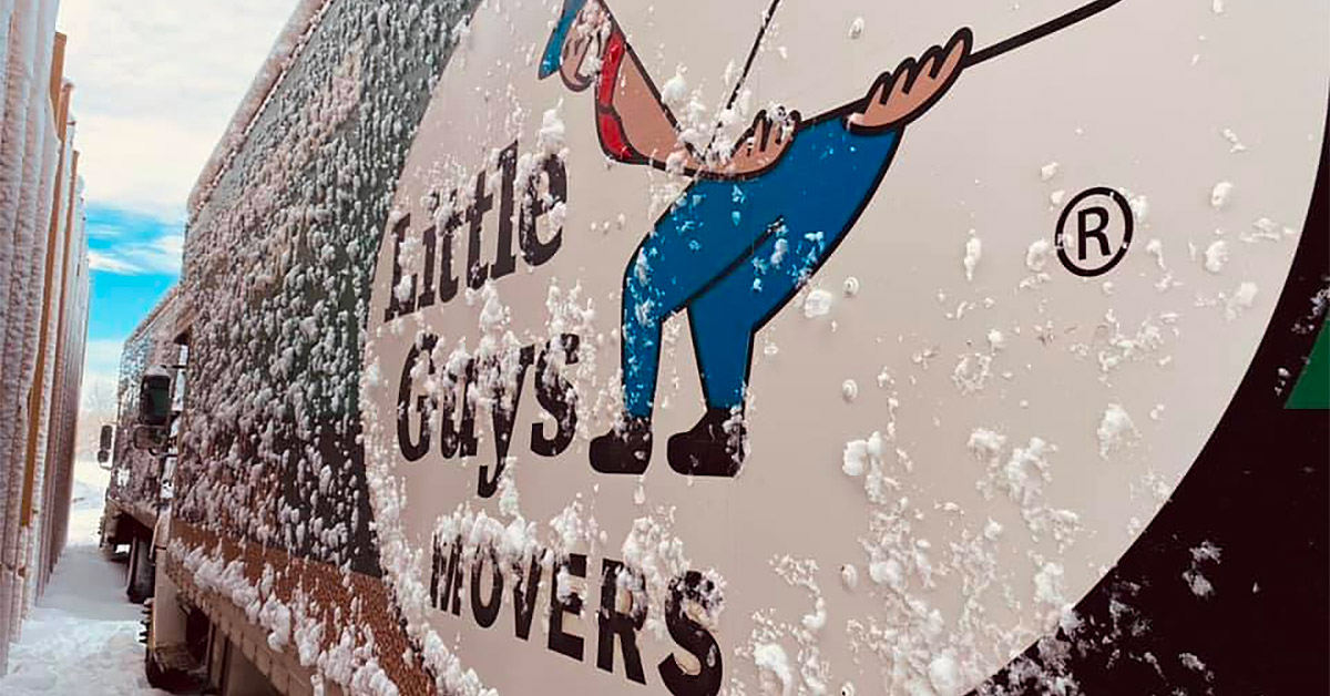 Close-up shot of a snowy Little Guys Movers moving truck.