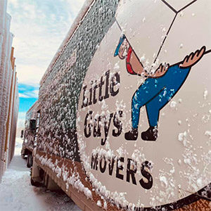 Close-up shot of a snowy Little Guys Movers moving truck.