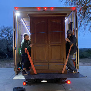 Little Guys Movers in Lexington use forearm lifting straps to move a large, heavy armoire.