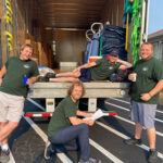 Four Little Guys movers pose with a moving truck