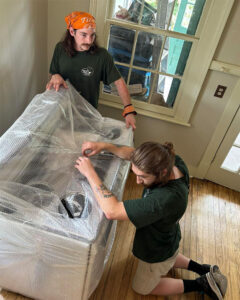 Two Little Guys Movers movers carefully wrap a large stove unit for transport.