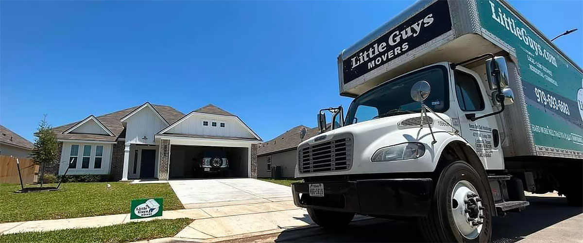 A Little Guys Movers moving truck is parked in front of a home in Bryan, Texas.