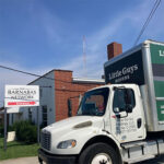 A Little Guys Movers moving truck in front of Greensboro's Barnabas Network building.