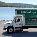 A Little Guys Movers moving truck posing by a lake.