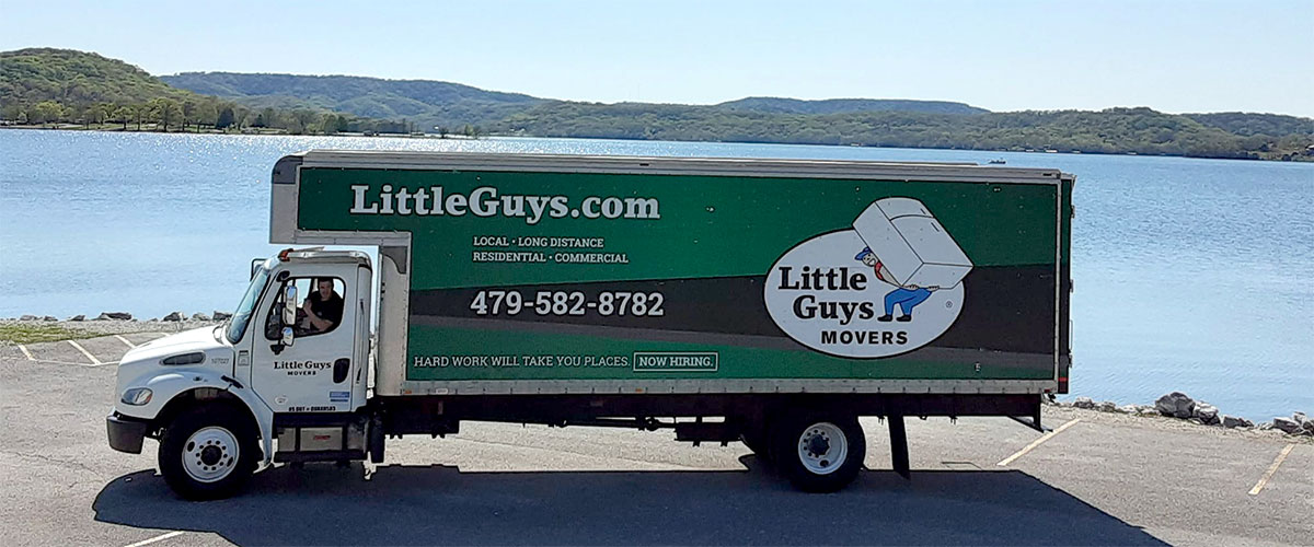 A Little Guys Movers moving truck posing by a lake.