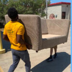 Little Guys Movers moves a donated love seat into Friends for Life's Adult Day Center.