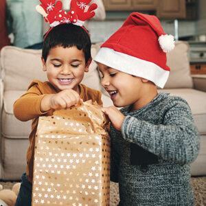 Two young children open a wrapped gift together on Christmas day.