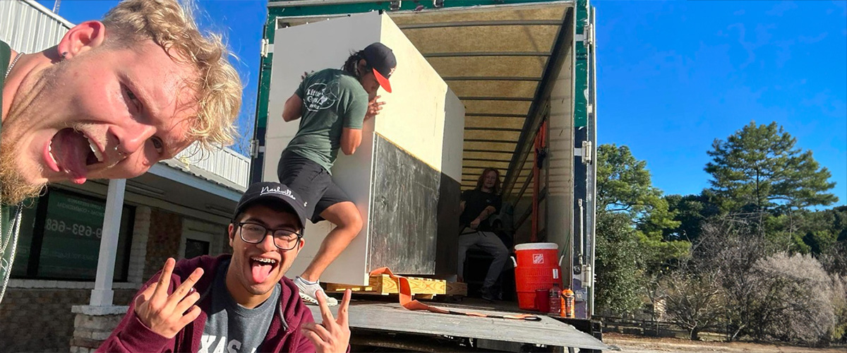 Several Little Guys Movers in Bryan/College Station expertly move a large, heavy piece of furniture into the moving truck.