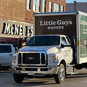 A Little Guys Movers moving truck drives by McNeill's appliance store in downtown Denton.