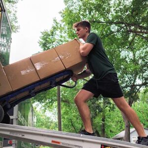 A mover with Little Guys Movers loads boxes into a U-Haul.