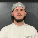 A mover wearing a white shirt and backwards cap poses for the camera.