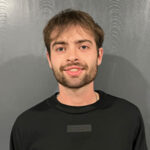 A mover wearing a black t-shirt smiles for the camera.