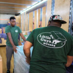Two Little Guys Movers movers unload a moving truck together.