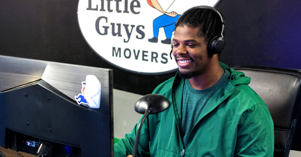 A friendly Little Guys Movers mover speaks with a customer on the phone, helping them book their move