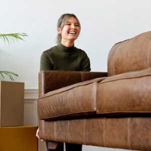 A woman helps carry a leather couch to donate it before a move.