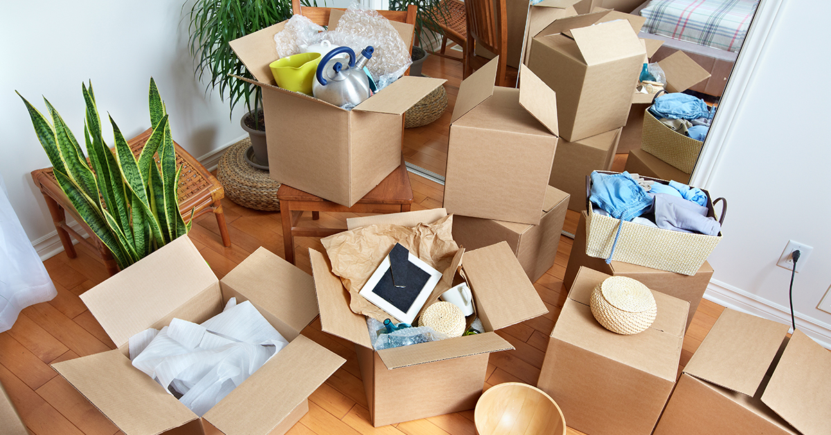 Several moving boxes are stacked in an apartment. Some boxes are open as if in the process of being packed.