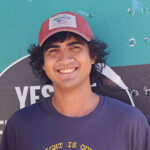 Smiling mover wearing a red hat in front of moving truck